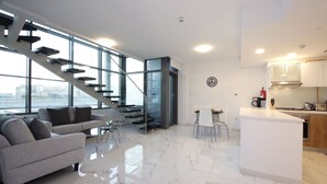 A modern living space with a staircase, a dining area, and a kitchen. - Luxury duplex in Raha lofts (Abu Dhabi)