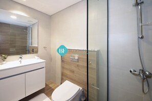 A modern bathroom with a glass shower enclosure, a white sink, and a wooden vanity.