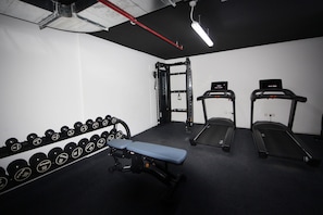 A gym with dumbbells, a bench, and treadmills.