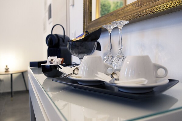 A tray with two white cups and a saucer, a black bowl, and a spoon on a glass table. - IMHOME - Porta Romana (Milan)