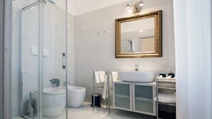A modern bathroom with a glass shower enclosure, a white sink, a toilet, and a vanity with a mirror. - IMHOME - Porta Romana (Milan)