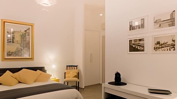 A bedroom with a bed, bedside table, chair, and artwork on the wall. - IMHOME - Porta Romana (Milan)