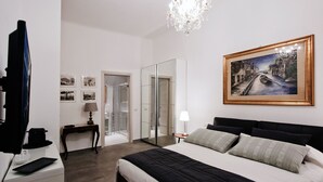 A hotel room with a bed, a painting, a chandelier, a mirror, and a television. - IMHOME - Porta Romana (Milan)