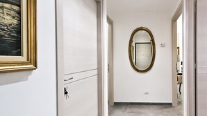 A hallway with a framed picture on the left, a mirror on the right, and a door at the end. - IMHOME - Porta Romana (Milan)