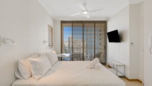 A bedroom with a bed, a desk, and a TV.