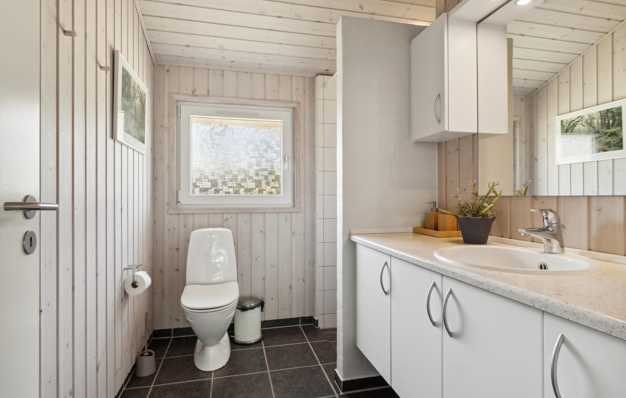 A modern bathroom with a toilet, sink, and mirror.