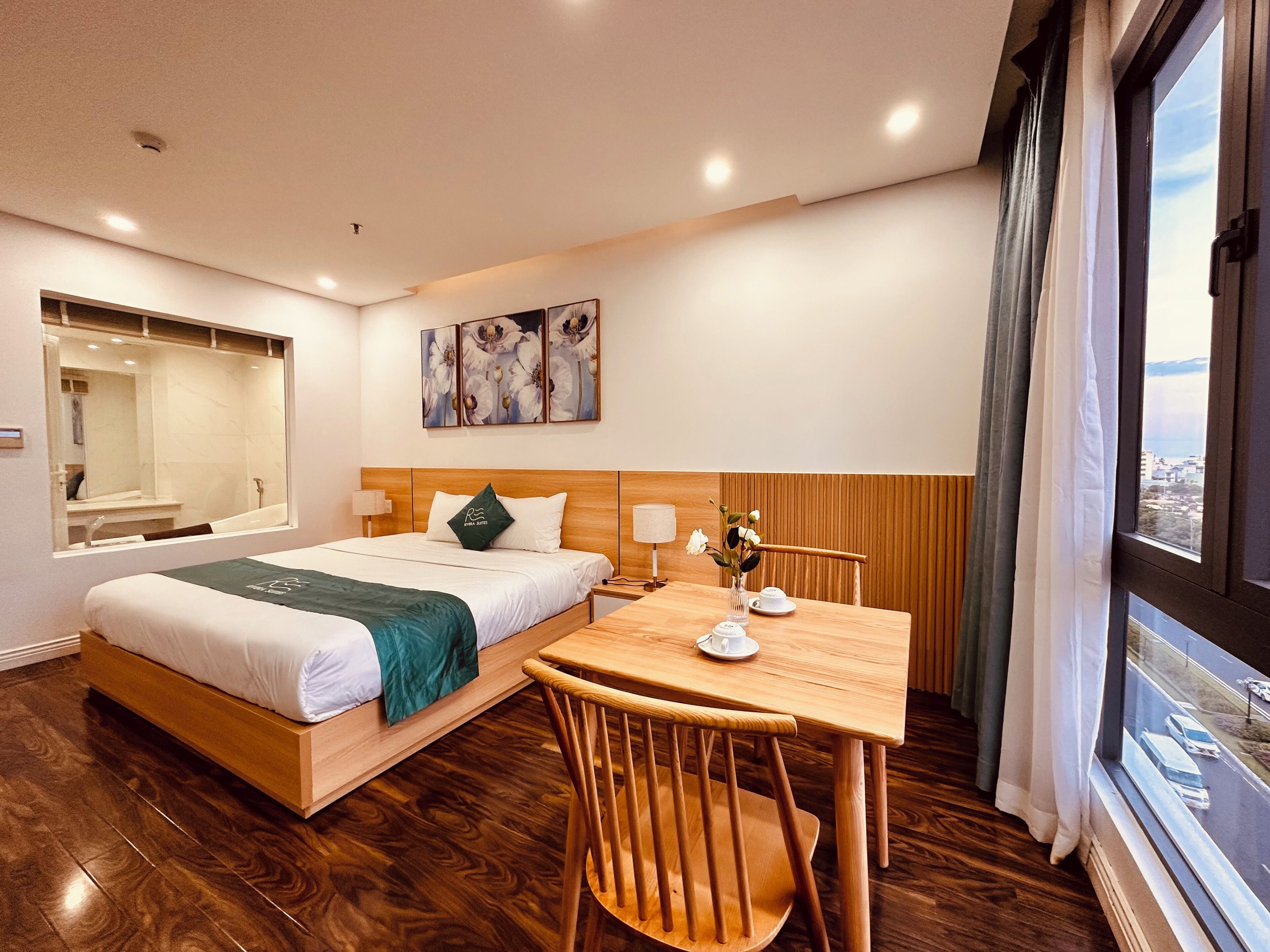 Ein Hotelzimmer mit einem Bett, einem Holztisch mit Stuhl, einem Fenster mit Blick und einem Spiegel.