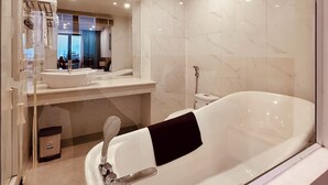 A modern bathroom with a large bathtub, a vanity with a mirror, and a shower area. - Rivera Suites (Da Nang)