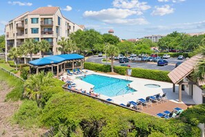 Een hotel met een zwembad, ligbedden en een overdekt terras.