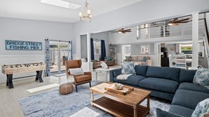 Uma sala de estar espaçosa com sofá, mesa de centro e mesa de futebol. Uma placa na parede diz "Bridge Street Fishing Pier".