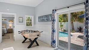 Um quarto com mesa de futebol de mesa, piscina e uma placa indicando "Bridge Street Fishing Pier".