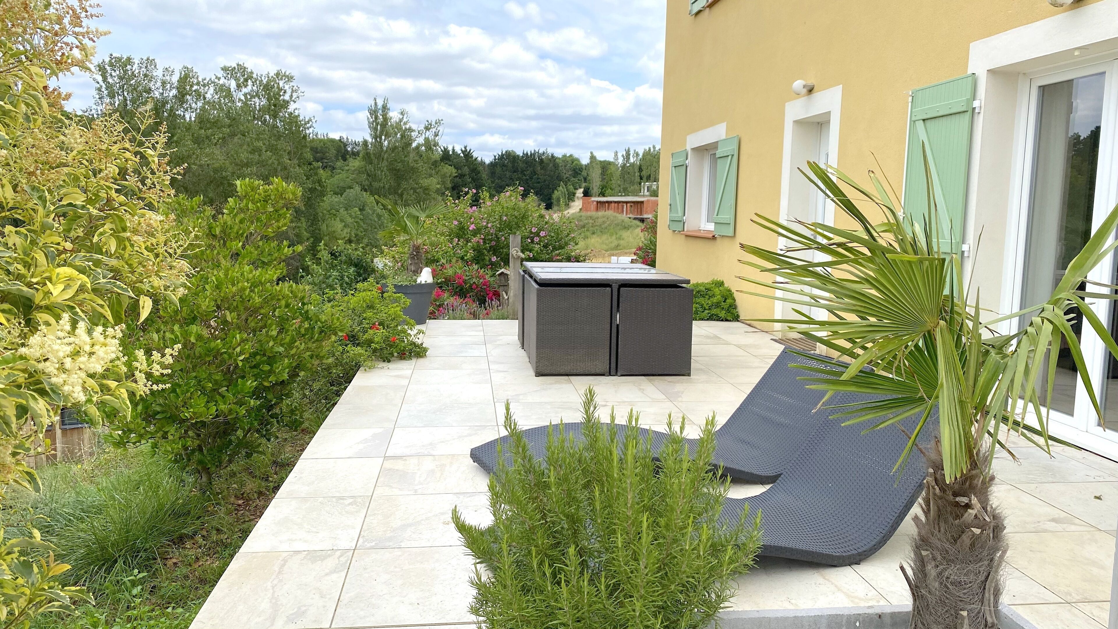 Eine Terrasse mit Sitzgelegenheit, einem kleinen Tisch und einem Blumentopf.
