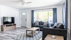 Un salon équipé d’un téléviseur à écran plat, d’un canapé, d’une table basse et d’un ventilateur de plafond.