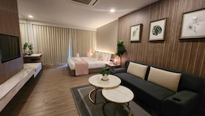 Una habitación de hotel moderna con una cama, un sofá, un televisor y una mesita.