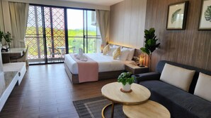 Una habitación de hotel moderna con cama, sofá, una mesita y balcón con vistas.
