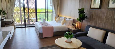 Una habitación de hotel moderna con cama, sofá, una mesita y balcón con vistas.