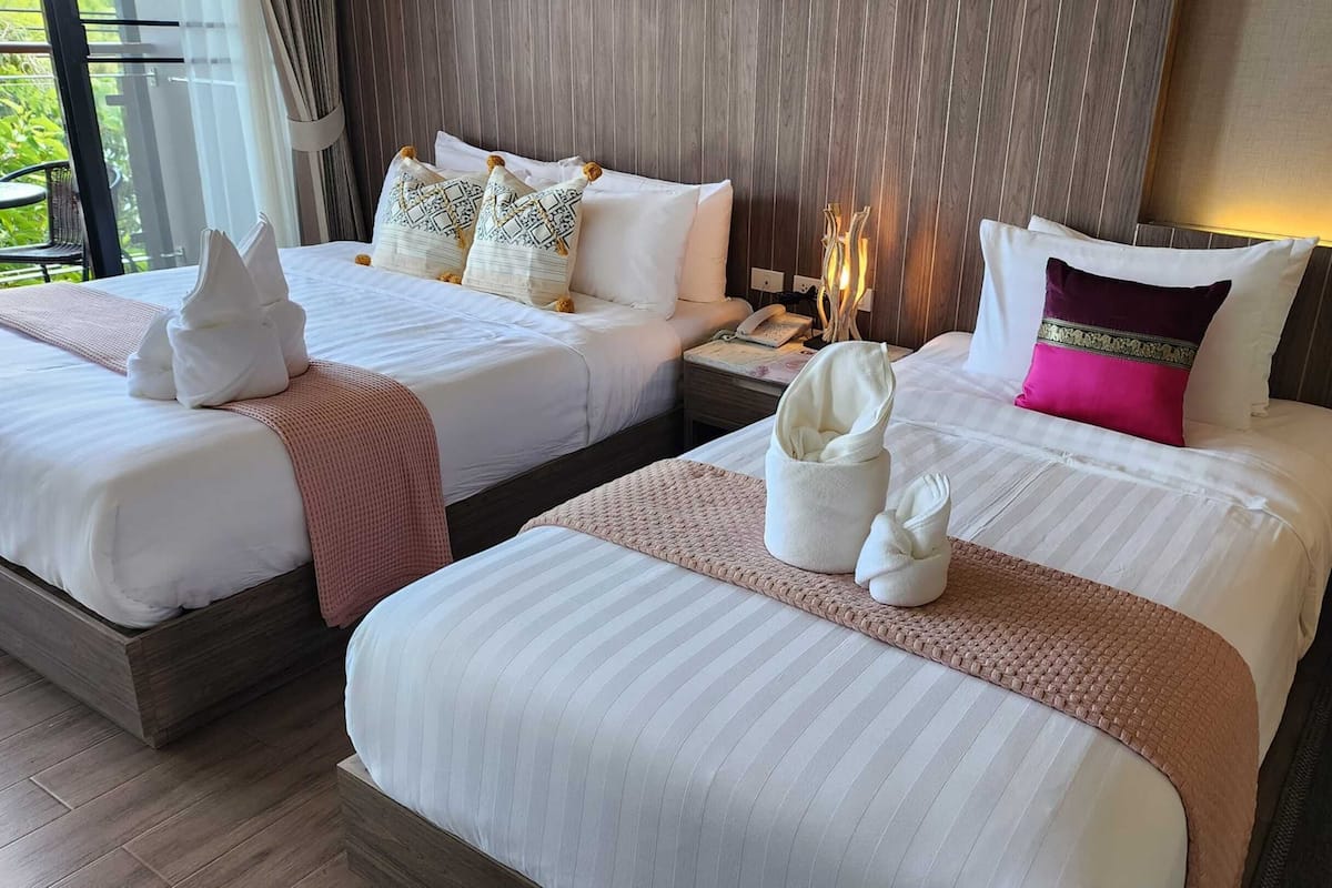 A hotel room with two beds, each with neatly arranged towels and pillows.