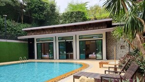 Un área de piscina moderna con una piscina cristalina, sillas de descanso y un edificio con amplios ventanales.
