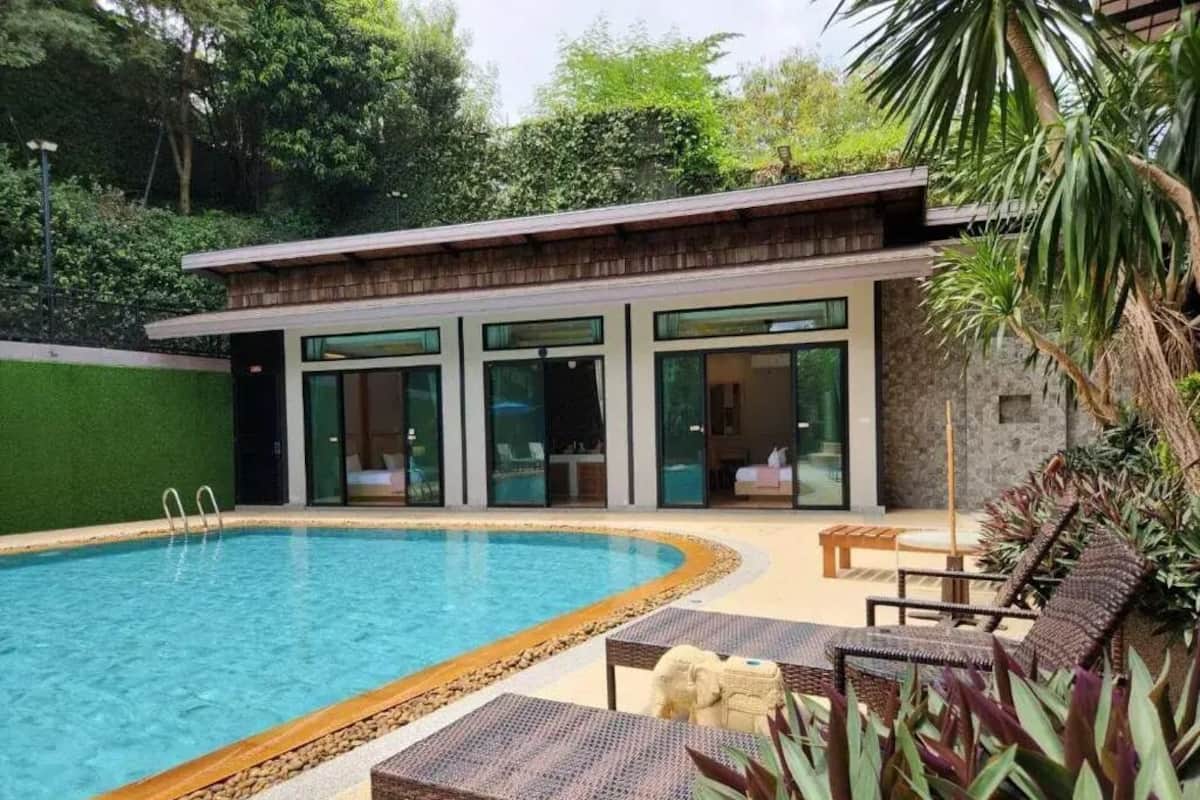 A modern pool area with a clear pool, lounge chairs, and a building with large windows.