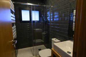 Ein kleines Badezimmer mit Duschkabine, weißer Toilette und Waschbecken.