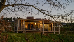 A modern house with a covered porch and multiple windows, surrounded by greenery. - Laje da Bica Agroturismo (Covilha)