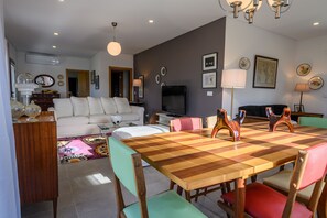 Ein Wohnzimmer mit einem weißen Sofa, einem Fernseher und einem Holzessttisch mit Stühlen.