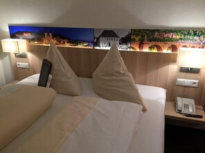 A hotel room with a bed, two bedside lamps, a phone, and a wall with a scenic mural. - Hotel Rose Heidelberg (Heidelberg)