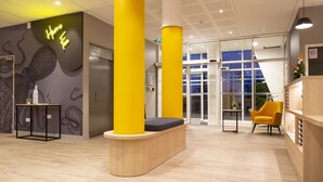 A modern interior with a reception desk, yellow pillars, and a seating area. - Appart Hotel Odalys City Le Havre Les Docks (Le Havre)