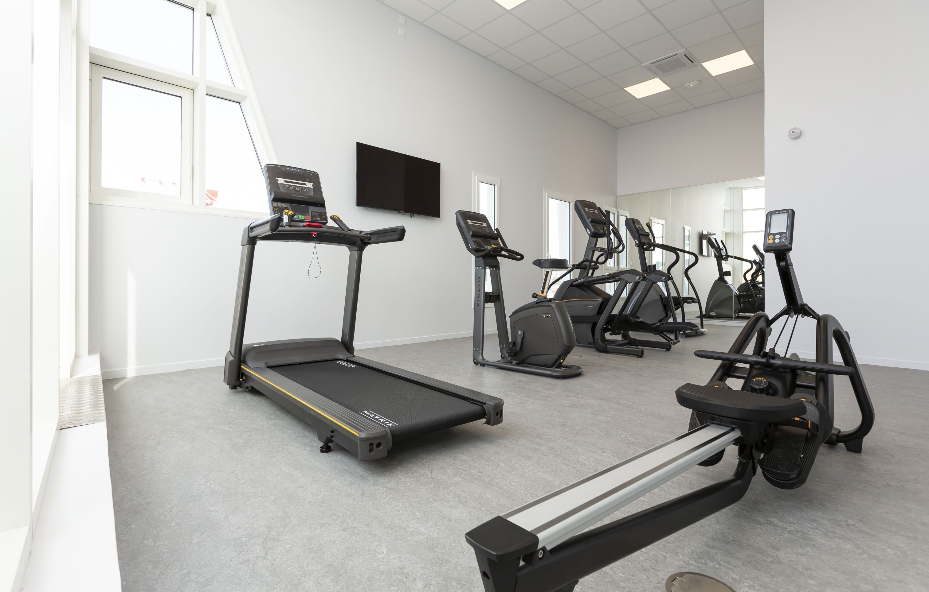 Un gimnasio con cintas de correr, elípticas y una bicicleta estática.