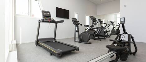 A gym with treadmills, elliptical machines, and a stationary bike.