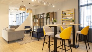A modern interior with a sofa, chairs, a table, and a bookshelf. - Appart Hotel Odalys City Le Havre Les Docks (Le Havre)