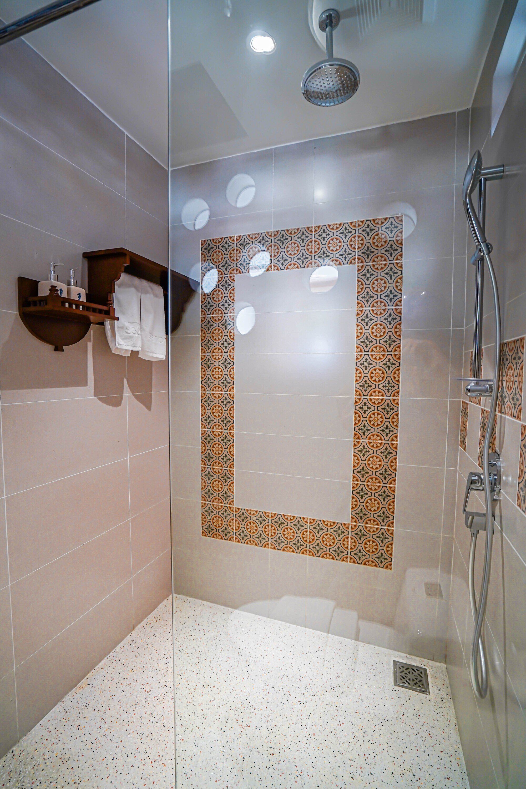 A modern shower with a glass door, a showerhead, and a handheld shower attachment.