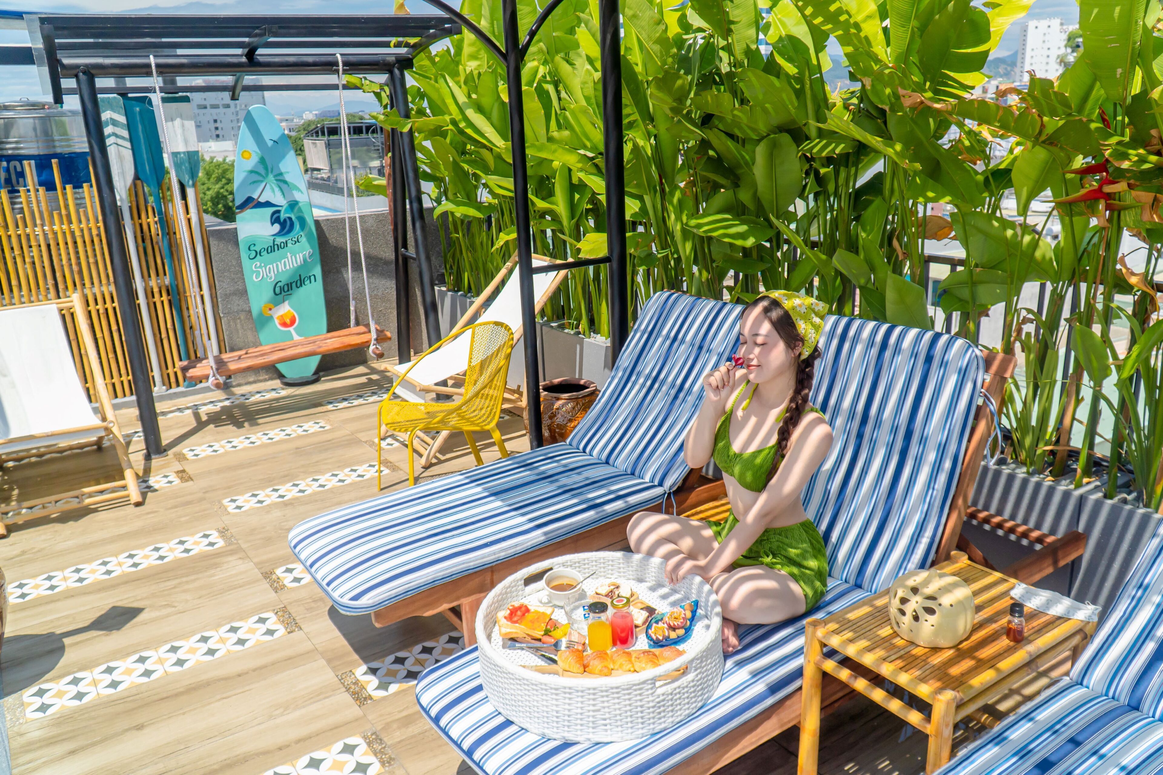 A person relaxing on a striped lounge chair with a tray of food and drinks.