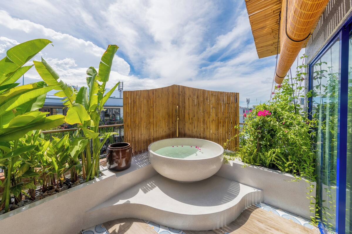 Terraza en la azotea con jacuzzi, plantas en macetas y cerramiento de bambú.