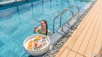A poolside area with a wooden deck and a pool.