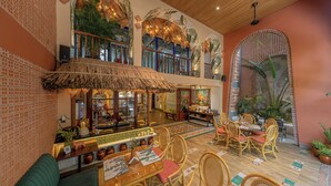 Un restaurant doté d’un toit de chaume, de meubles en osier et d’une décoration de style tropical.