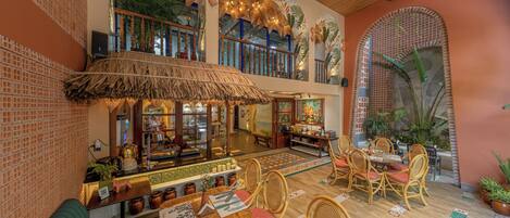 A restaurant with a thatched roof, wicker furniture, and tropical decor.