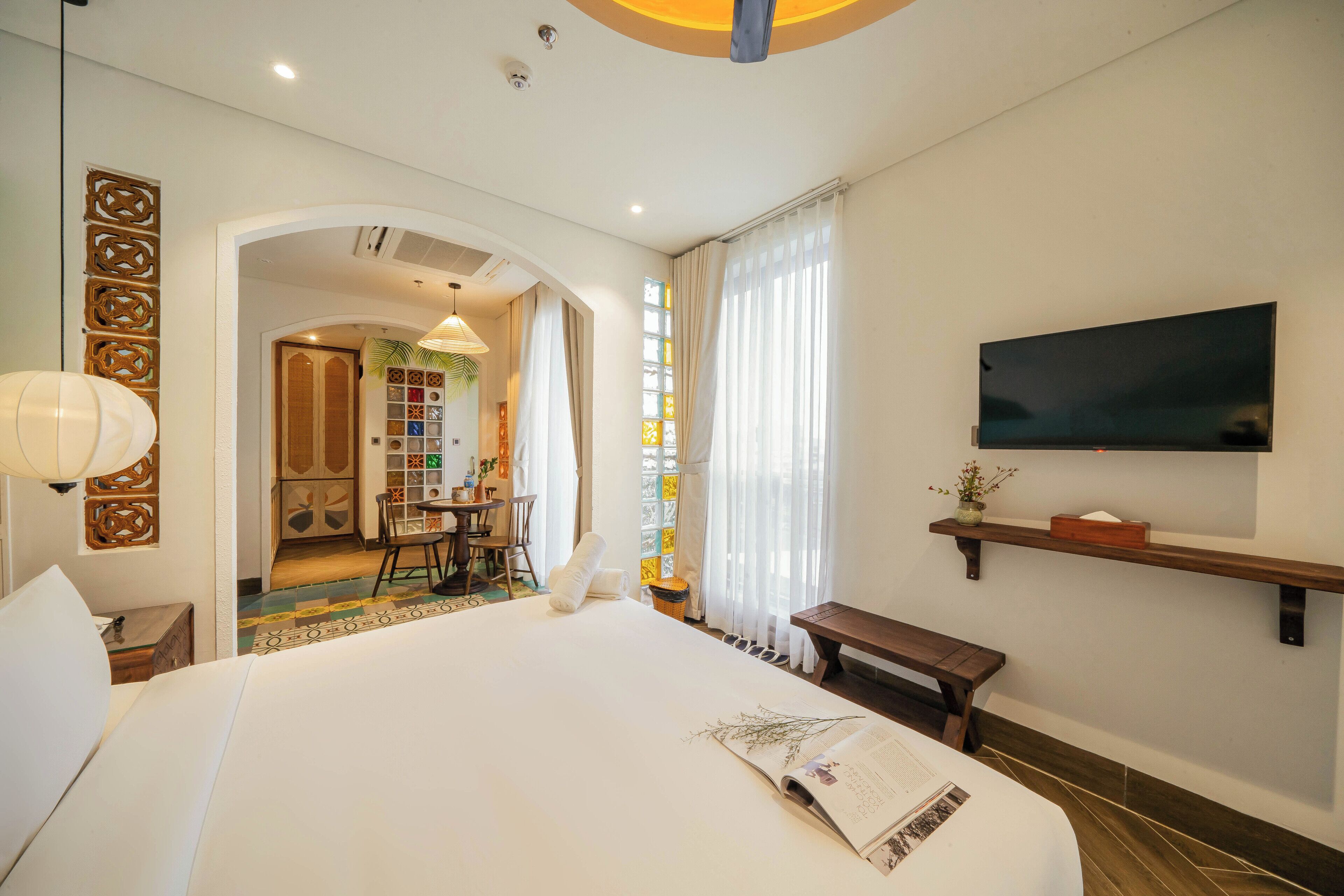 A hotel room with a large bed, a TV mounted on the wall, and a small table.