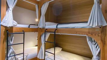 A corner room with three bunk beds, each with a curtain, and wooden walls with room numbers 422 and 426.