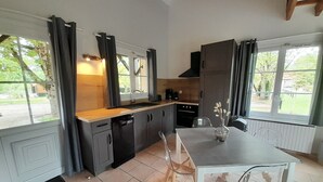 Una cocina moderna con gabinetes oscuros, una encimera blanca y una mesa de comedor con sillas.