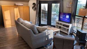 Una sala de estar con sofá, una silla, un televisor sobre un mueble bajo y un aparador de madera.
