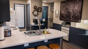 Una cocina moderna con una isla central, taburetes de bar, una cafetera y un mapa en la pared.