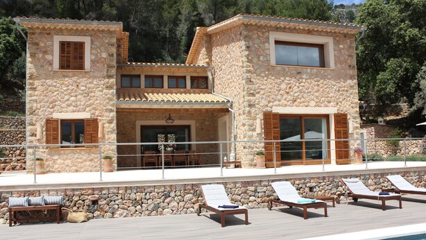 A stone building with a pool area, including lounge chairs and a bench. - Private villa with breathtaking views and private pool. (Port de Sóller)