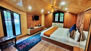 A wooden-paneled bedroom with a bed, bedside table, and a TV mounted on the wall. - DK Residency - Shimla (Shimla)