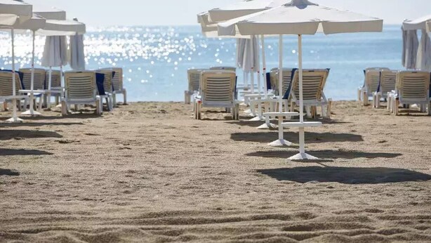 A beach with rows of white sun loungers and umbrellas, arranged on sandy ground. - Hotel Klisura (Sunny Beach)
