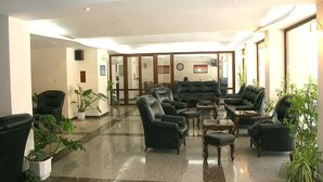 A lobby with leather sofas, a coffee table, and potted plants. - Hotel Klisura (Sunny Beach)