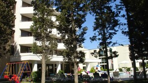 A multi-story building with balconies, a playground, and a pool area with sun loungers. - Hotel Klisura (Sunny Beach)