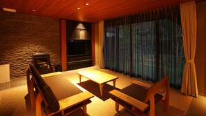 Una habitación acogedora con pared de piedra, chimenea, un gran ventanal con cortinas y una mesa de comedor de madera con sillas.