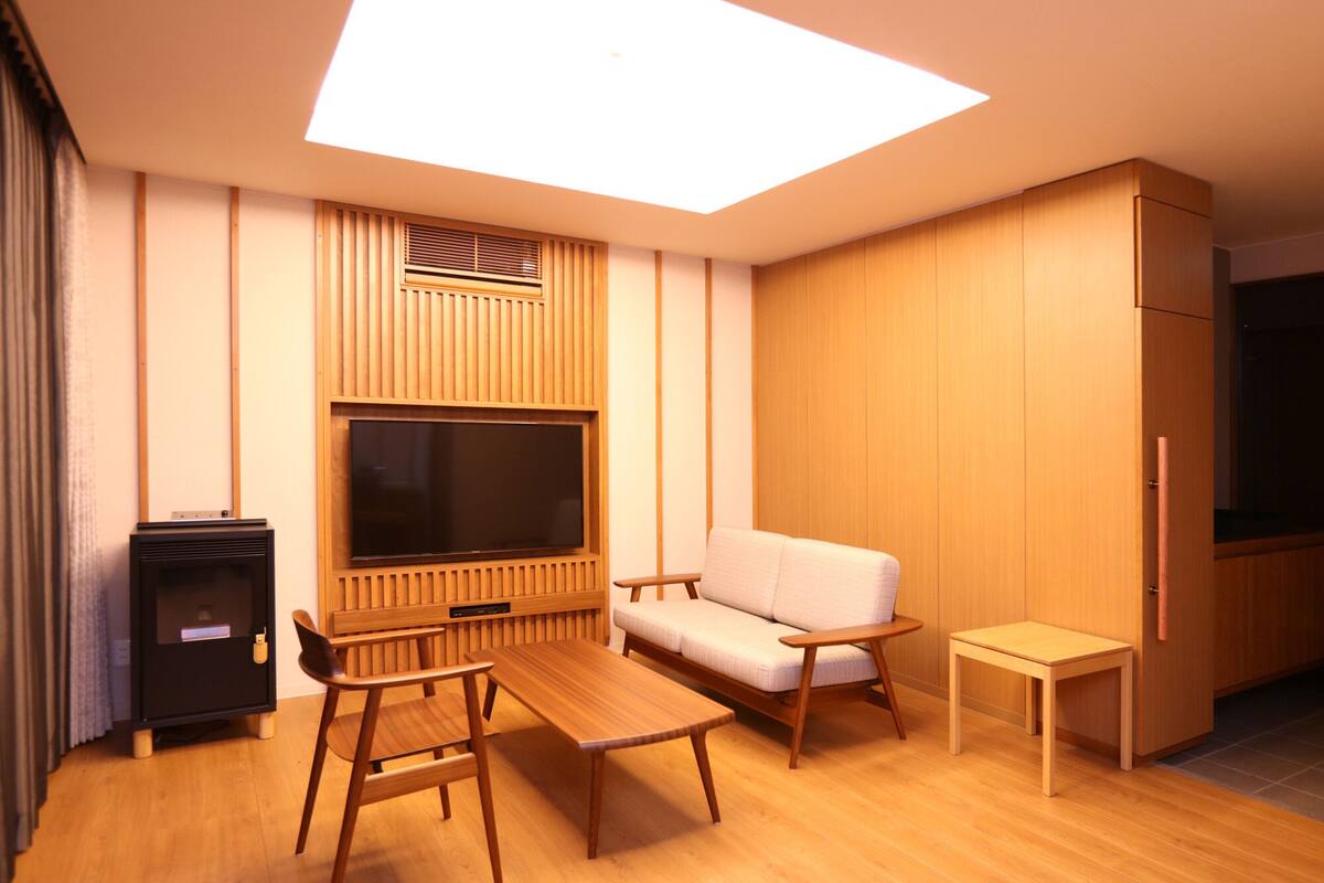 A modern living room with a flat-screen TV, wooden furniture, and a built-in cabinet.