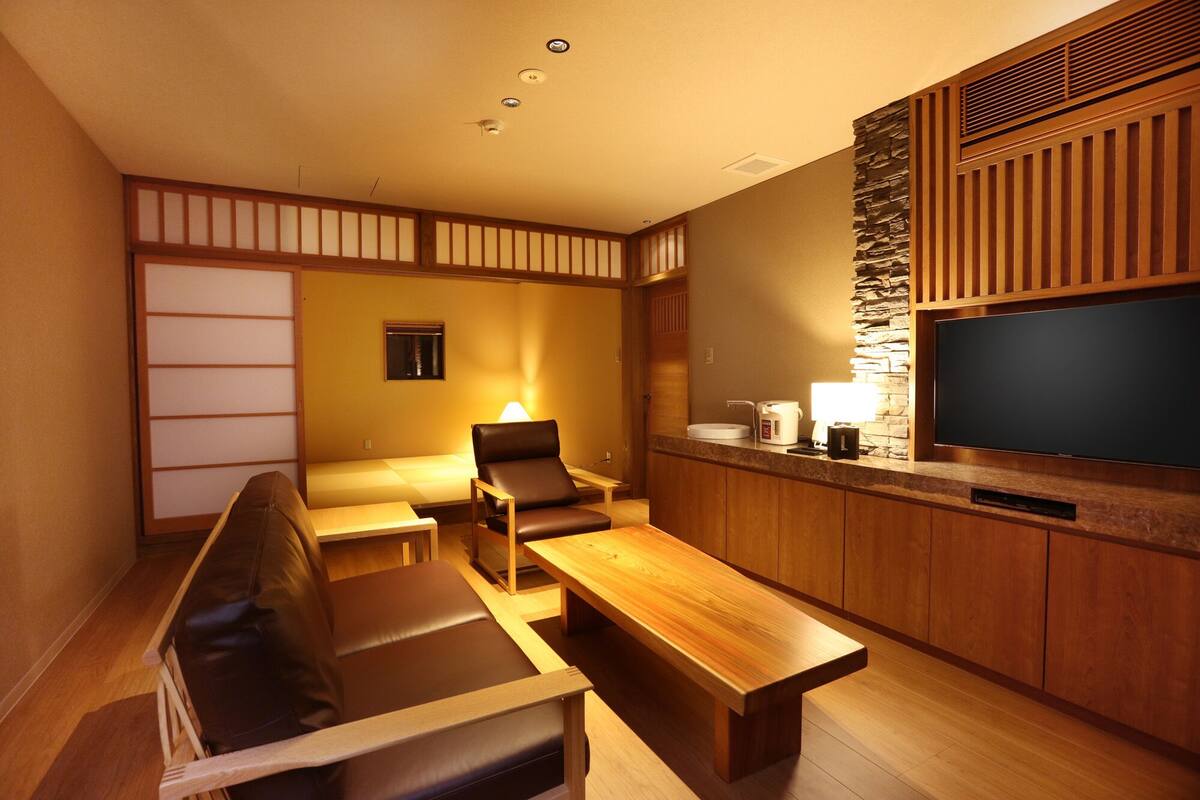A modern living room with a sofa, a coffee table, a TV, and a stone accent wall.